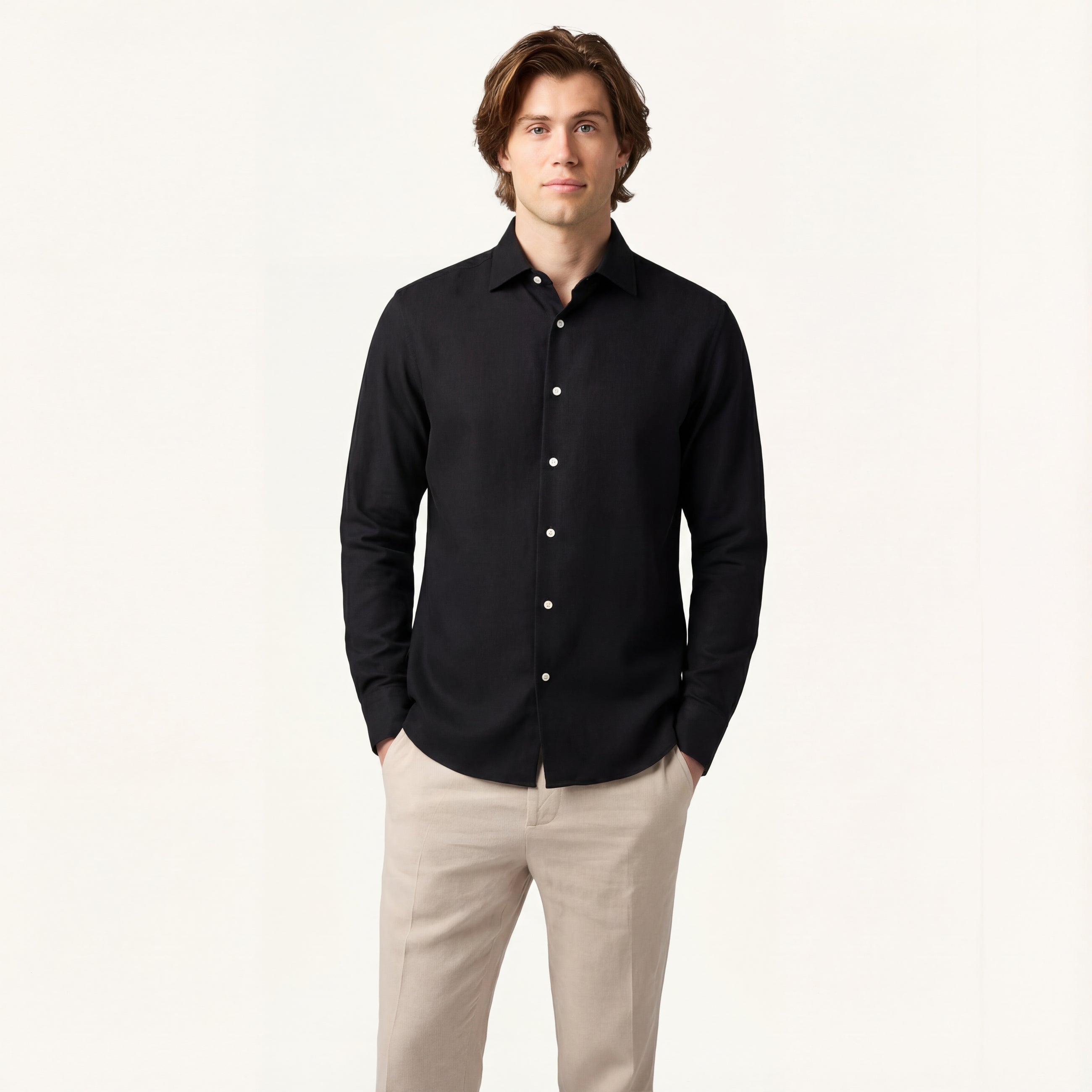 Man wearing a black button-up shirt and beige pants on a white background