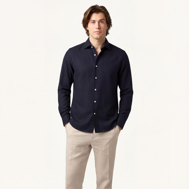 Man wearing a navy button-up shirt and beige pants on a white background
