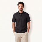 Model wearing obsidian black linen polo shirt